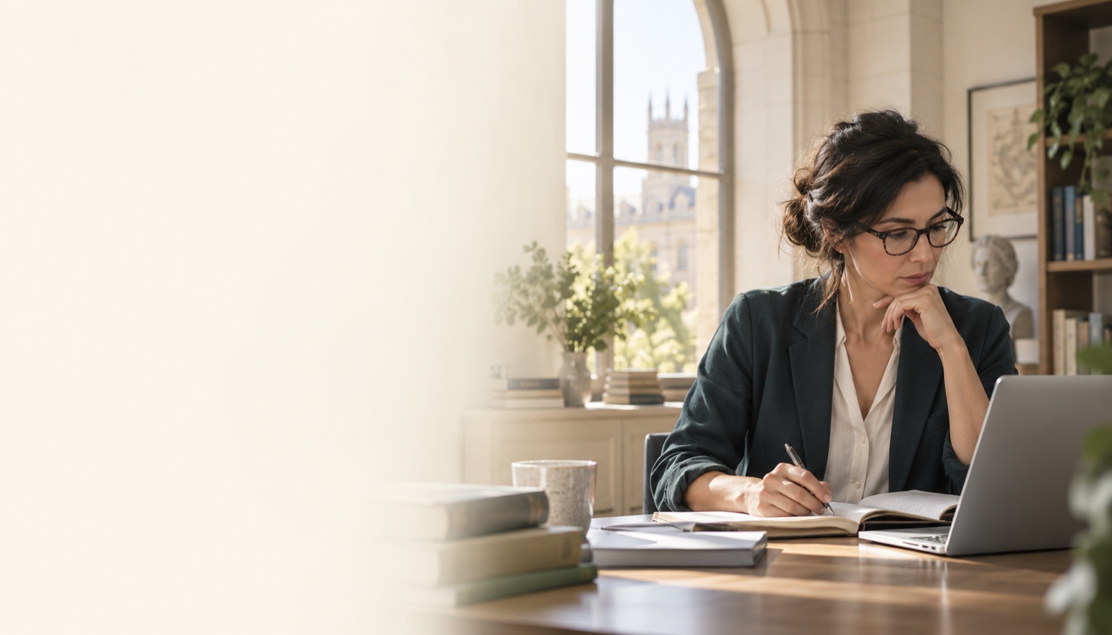 Illustrative researcher reviewing papers and taking notes beside a laptop